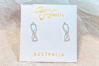 Infinity shaped silver stud earrings on a white display card with a textured white background
