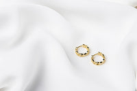 A pair of interlinked gold vermeil hoop earrings on a white background, showcasing a patterned design.