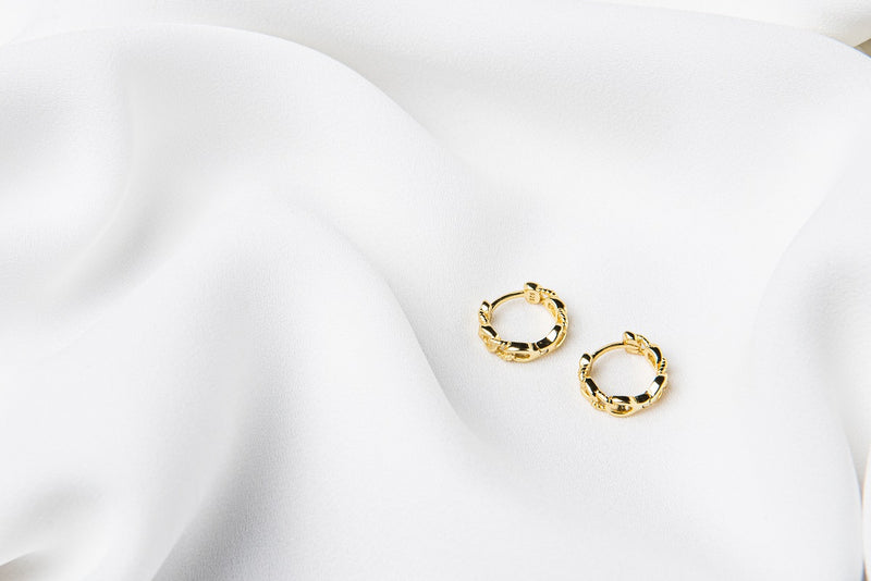 A pair of interlinked gold vermeil hoop earrings on a white background, showcasing a patterned design.