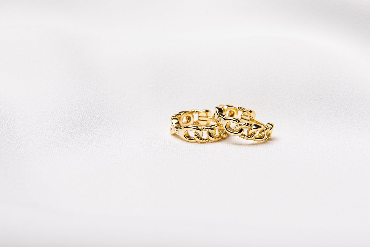 A pair of interlinked gold vermeil hoop earrings on a white background, showcasing a patterned design.