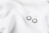 A pair of interlinked silver hoop earrings on a white background, showcasing a patterned design.
