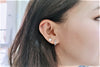 A  women wearing a pair of interlinked silver hoop earrings.