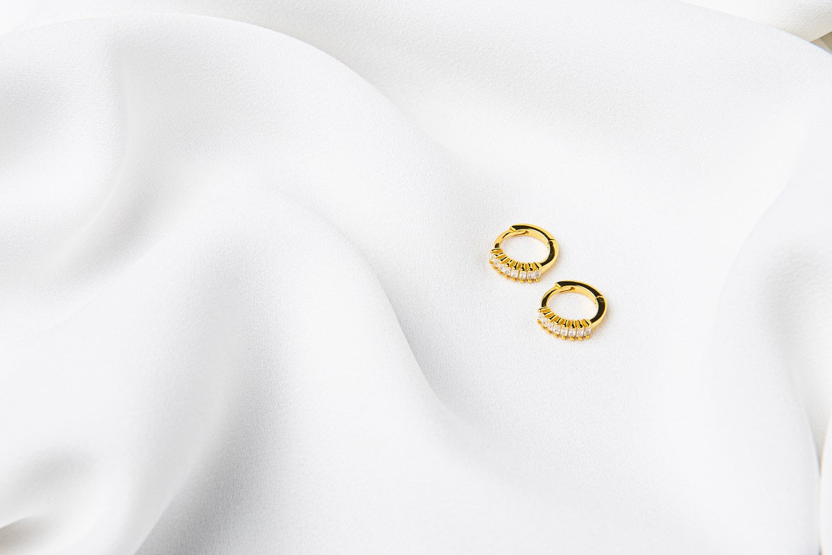 A pair of gold vermeil earrings with cubic zirconias on a white cloth background