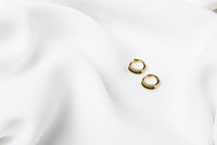 A pair of gold vermeil earrings with black cubic zirconias on a white cloth background