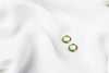 A pair of gold vermeil earrings with green cubic zirconias on a white cloth background