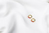 A pair of gold vermeil earrings with pink cubic zirconias on a white cloth background