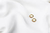 A pair of gold vermeil earrings with purple cubic zirconias on a white cloth background