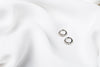 A pair of silver earrings with cubic zirconias on a white cloth background