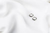 A pair of silver earrings with black cubic zirconias on a white cloth background