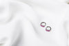 A pair of silver earrings with purple cubic zirconias on a white cloth background