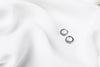 A pair of silver earrings with purple cubic zirconias on a white cloth background