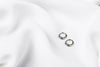 A pair of silver earrings with rainbow cubic zirconias on a white cloth background