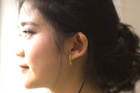 Model wearing a gold stud earring with a blurred background