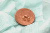 A pair of rose gold stud earrings with butterfly backs, displayed on a wood surface.