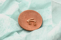 A pair of rose gold stud earrings with butterfly backs, displayed on a wood surface.