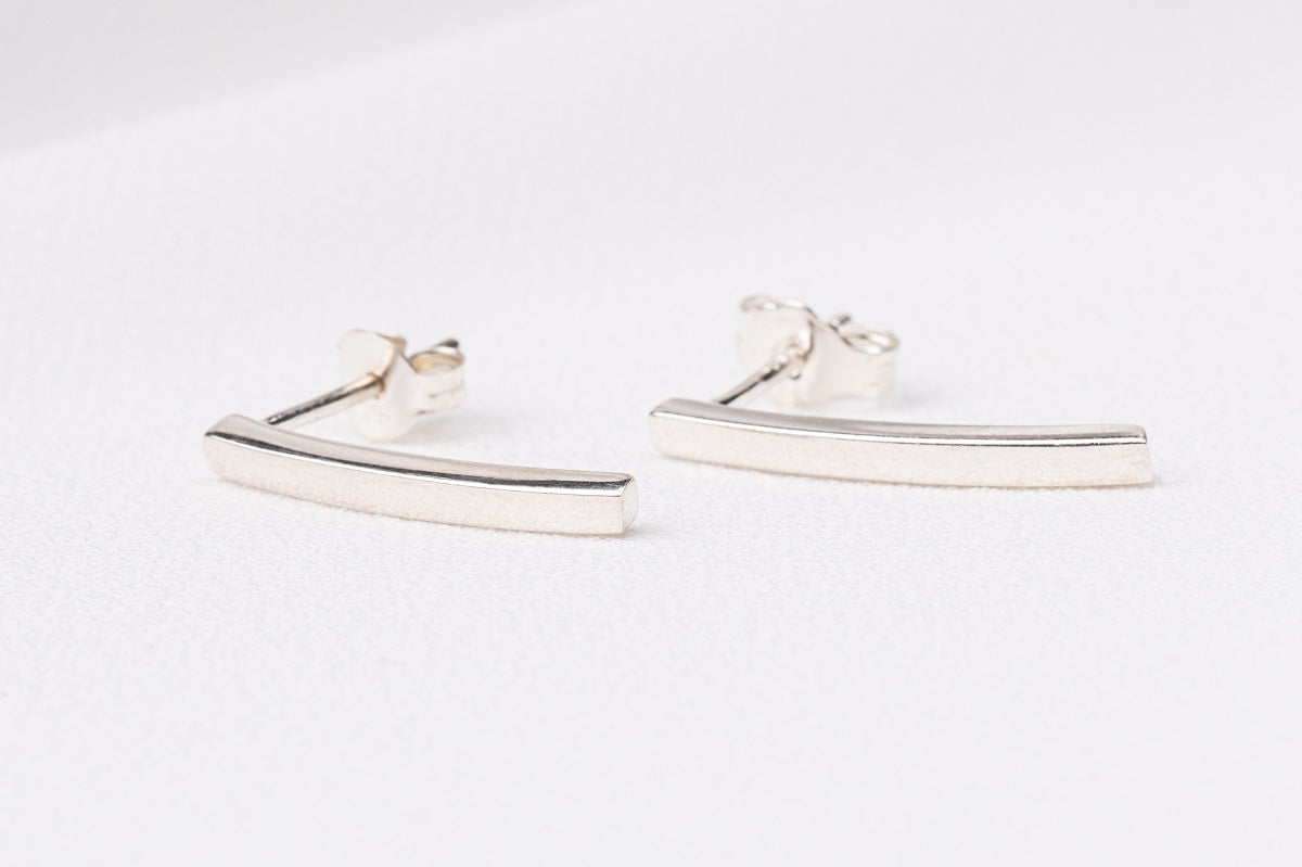 A pair of sterling silver stud earrings with butterfly backs, displayed on a white surface.