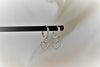 A pair of silver hoop earrings with heart-shaped dangles, displayed on a white background.