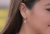 A silver earring with a white pearl worn by a woman