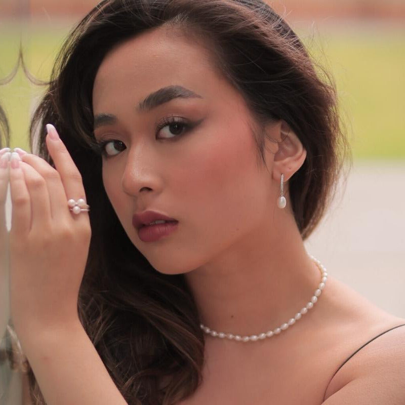 A silver earring with a white pearl worn by a woman