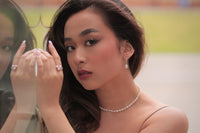 A silver earring with a white pearl worn by a woman