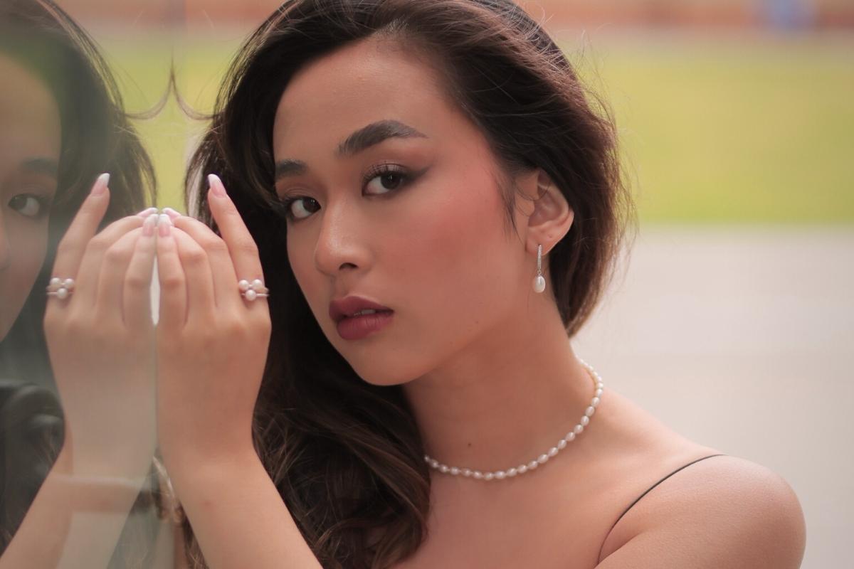 A silver earring with a white pearl worn by a woman