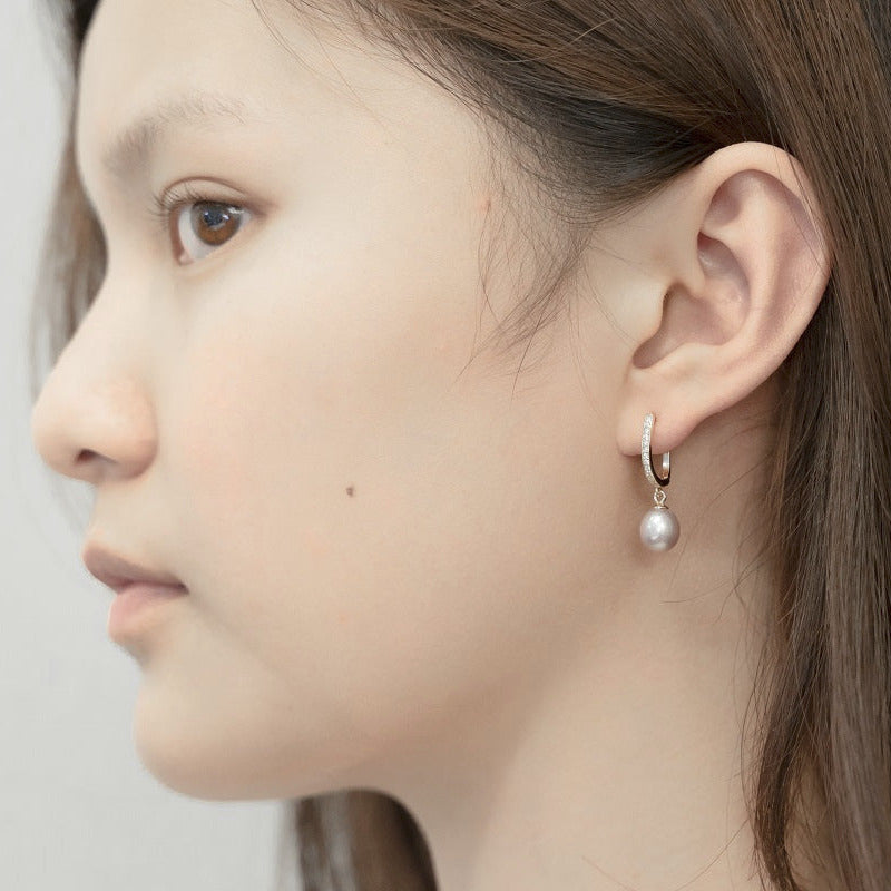 A silver earring with a white pearl worn by a woman