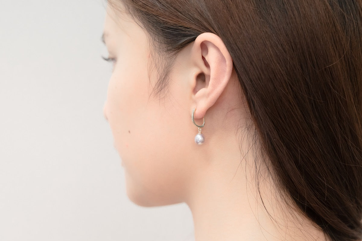 A silver earring with a white pearl worn by a woman