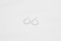 A pair of silver pearl earrings with a semi-dangle design on a white background.