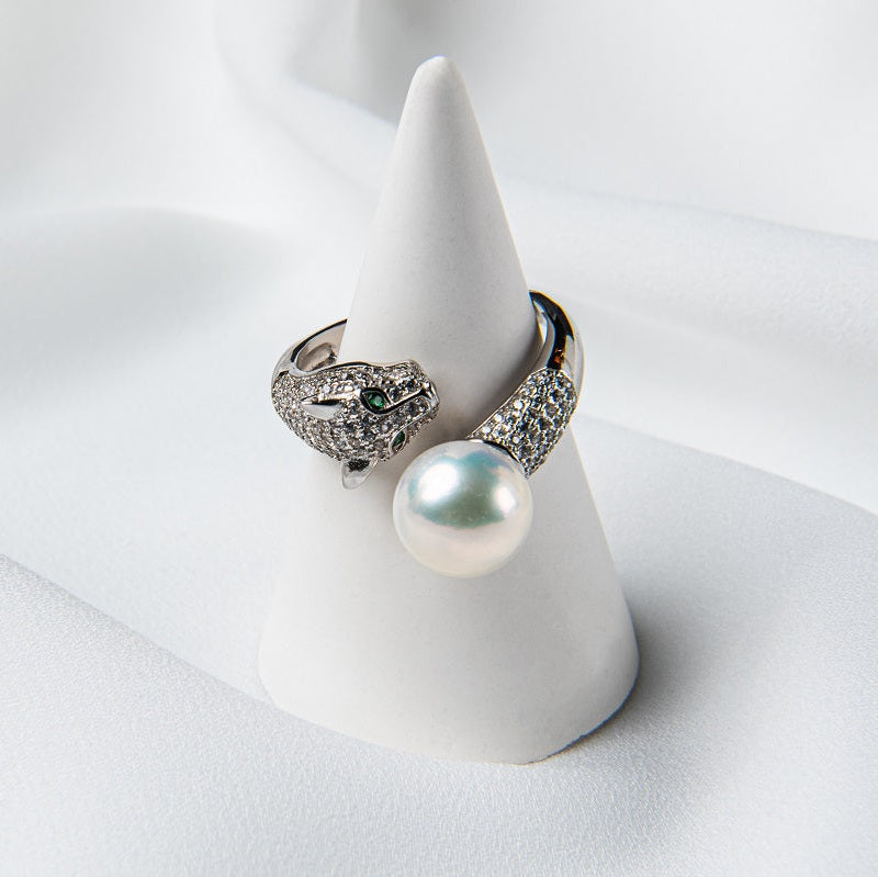 A silver panther design ring on a cone stand with a pearl centerpiece.