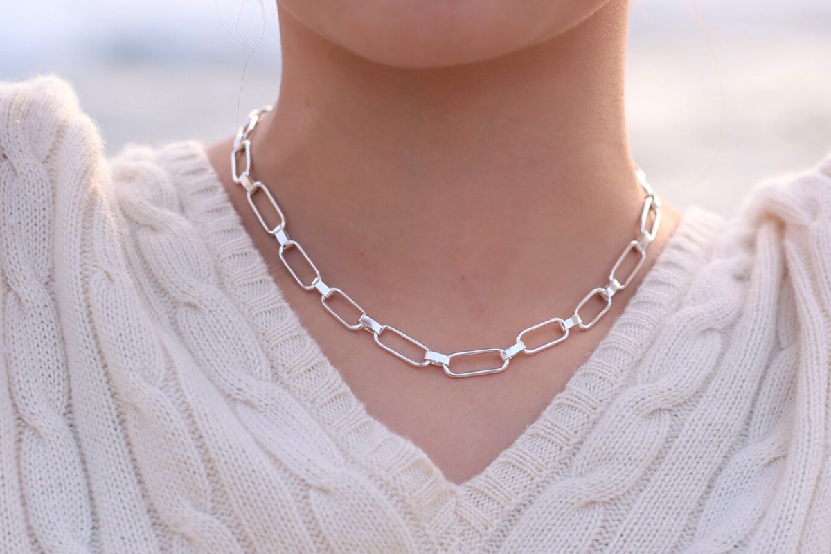 Large link silver chain necklace worn by a woman