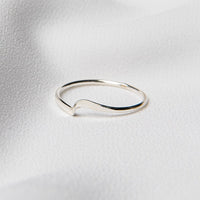 A polished silver ring on a white silky surface.