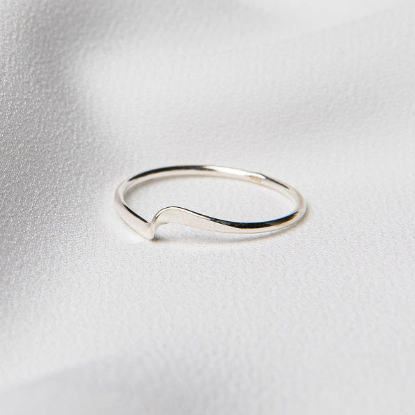 A polished silver ring on a white silky surface.