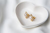 A pair of pearl button stud gold vermeil earrings placed on a white fabric surface.