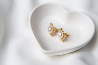 A pair of pearl button stud gold vermeil earrings placed on a white fabric surface.