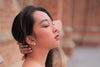 A pair of pearl button stud earrings worn by an asain woman model