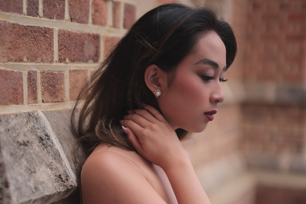 A pair of pearl button stud earrings worn by an asain woman model