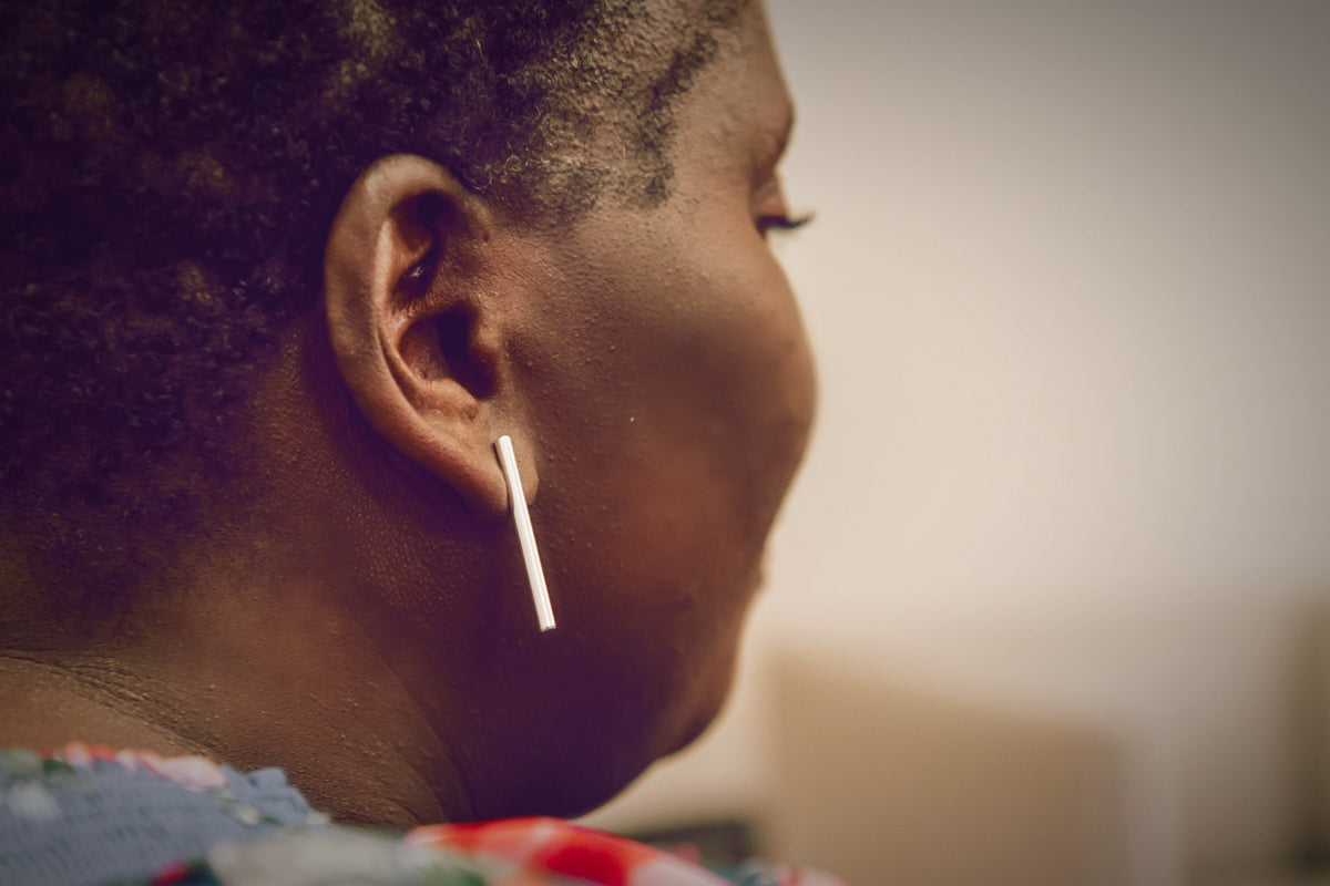 A pair of silver long bar stud earrings on a woman model