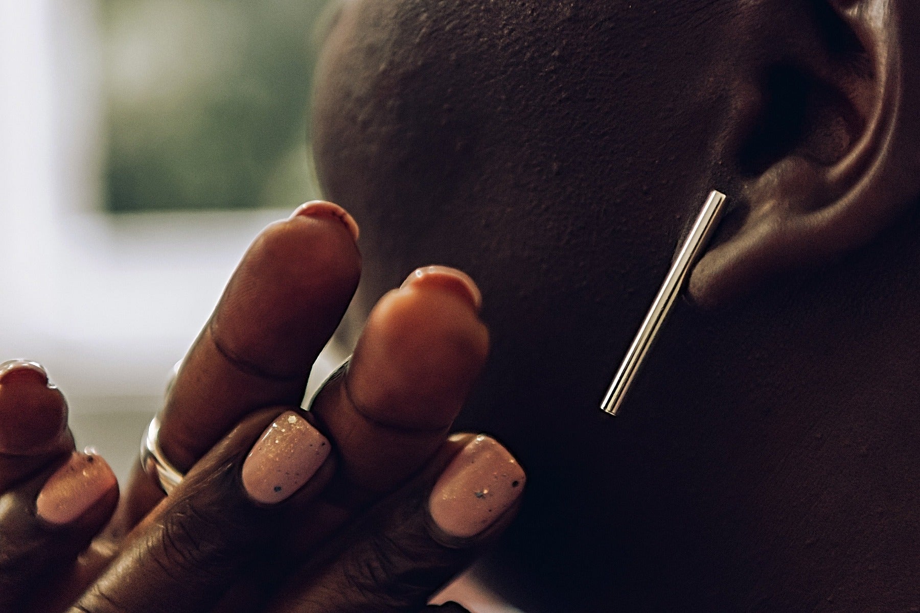 A pair of silver long bar stud earrings on a woman model