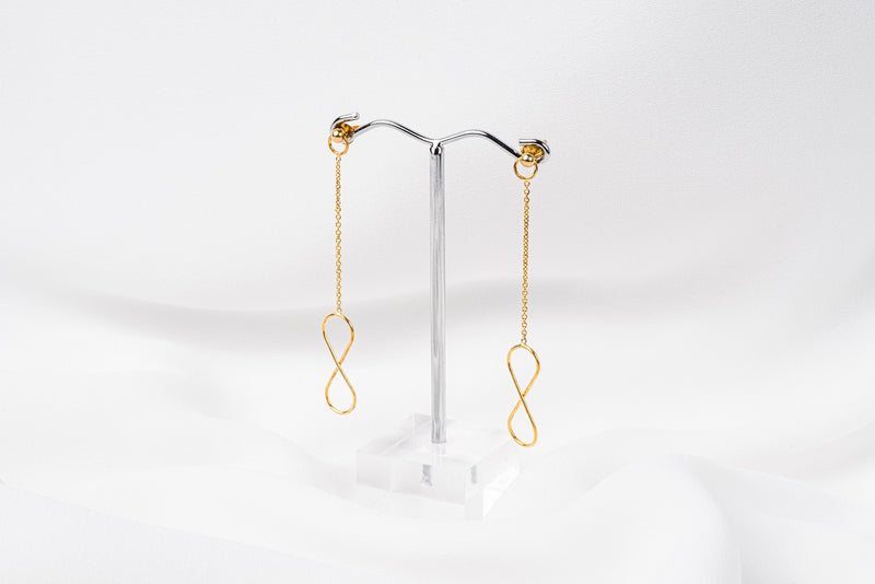 A pair of gold-colored dangle earrings with butterfly backs, displayed against a white background.