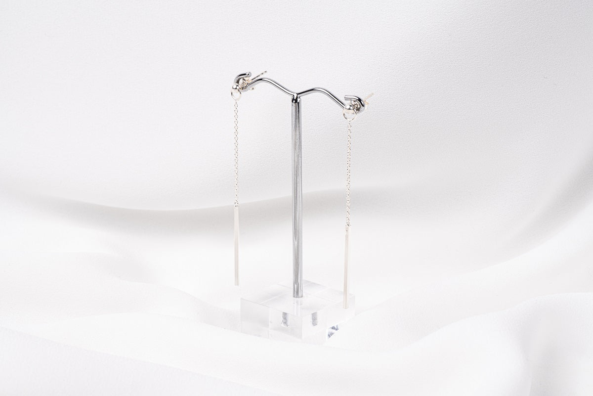 A pair of silver-colored dangle earrings with butterfly backs, displayed against a white background.