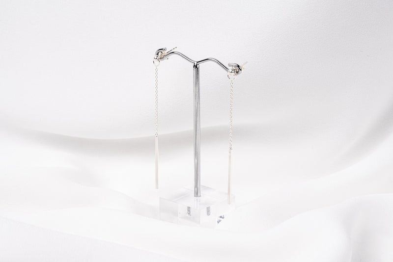 A pair of silver-colored dangle earrings with butterfly backs, displayed against a white background.