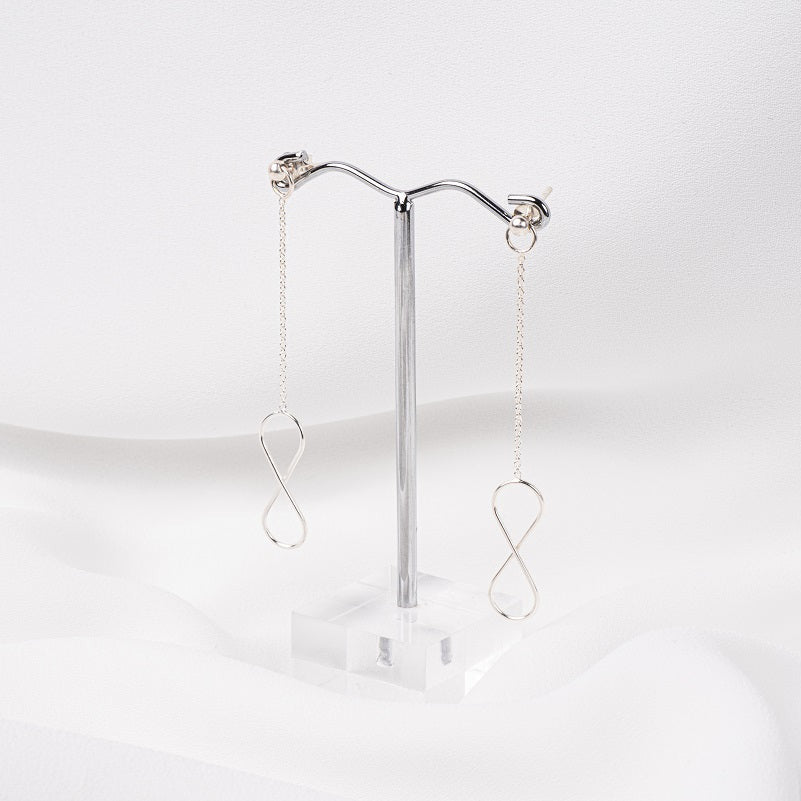 A pair of silver-colored dangle earrings with butterfly backs, displayed against a white background.
