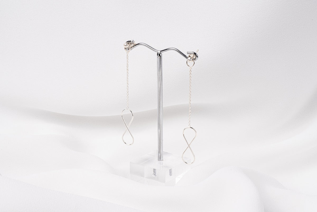 A pair of silver-colored dangle earrings with butterfly backs, displayed against a white background.