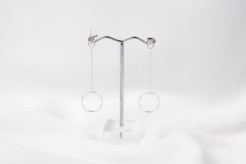 A pair of silver-colored dangle earrings with butterfly backs, displayed against a white background.