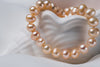 A sterling silver freshwater champagne pearl necklace displayed on a white shell dish.