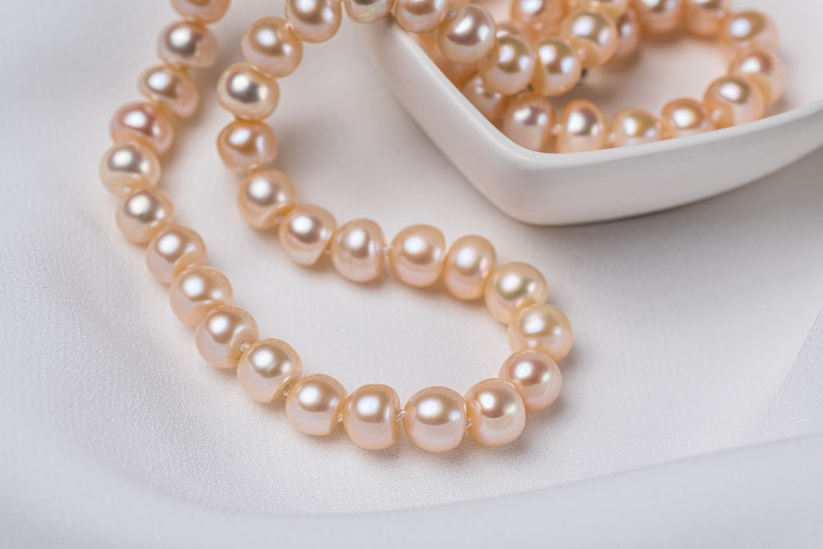 A freshwater champagne pearl necklace displayed on a heart shaped dish