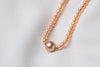 A string of pearls with a larger champagne pearl gold vermeil chain in the center displayed on a white background.