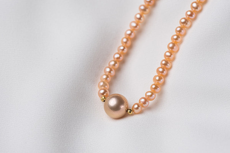 A string of pearls with a larger champagne pearl gold vermeil chain in the center displayed on a white background.