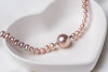 A string of pearls with a larger pearl in the center displayed on a white heart-shaped dish.