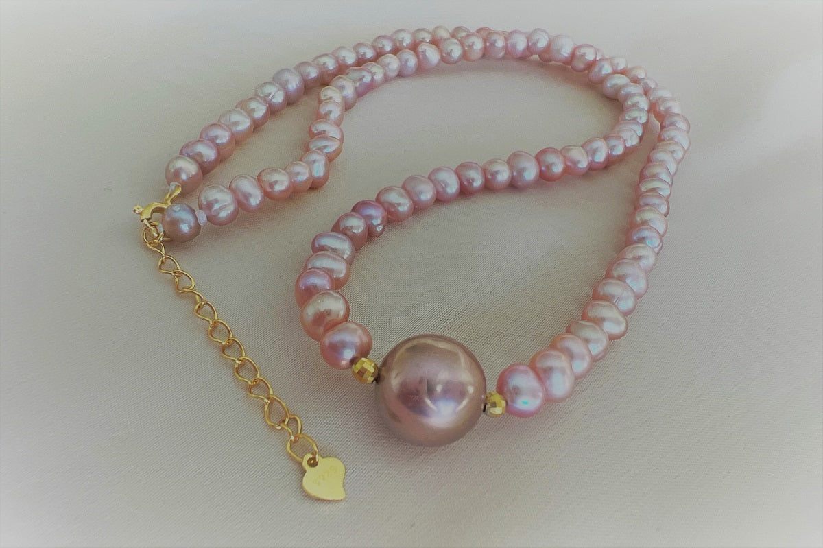 A string of pearls with a larger lavender pearl gold vermeil chain in the center displayed on a white background.